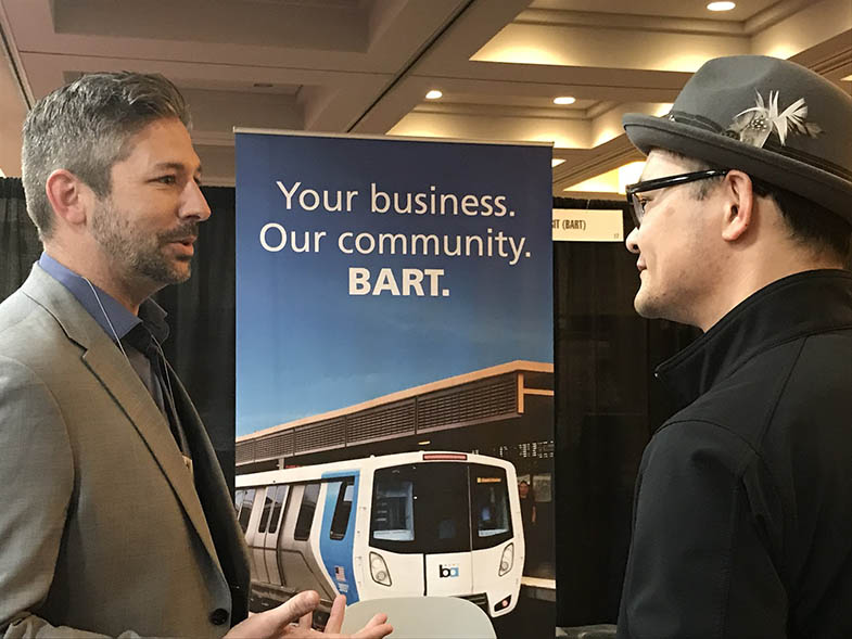 Fei Liu of BART's Office of Civil Rights, right, talks with a conference attendee