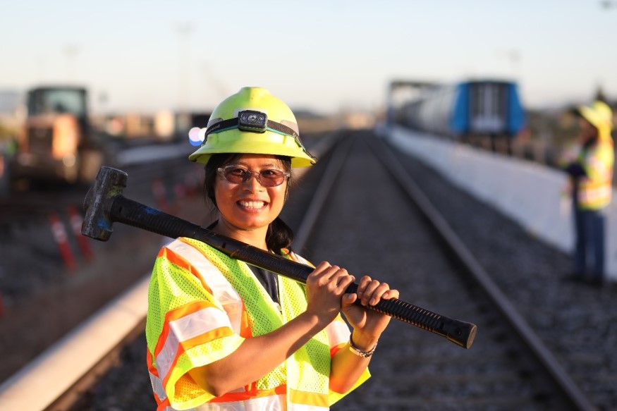 Thu Nguyen in safety gear on a track with a tool