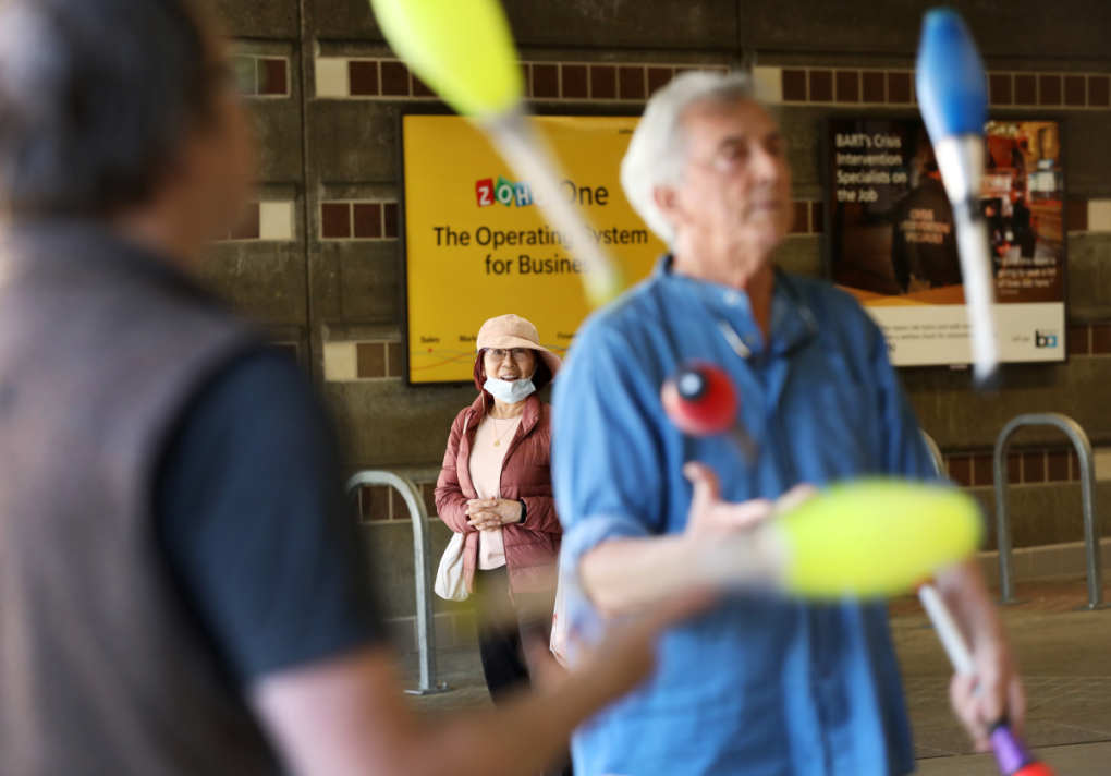 A rider leaving Castro Valley Station stops to watch the jugglers on a Tuesday evening meetup in July. 