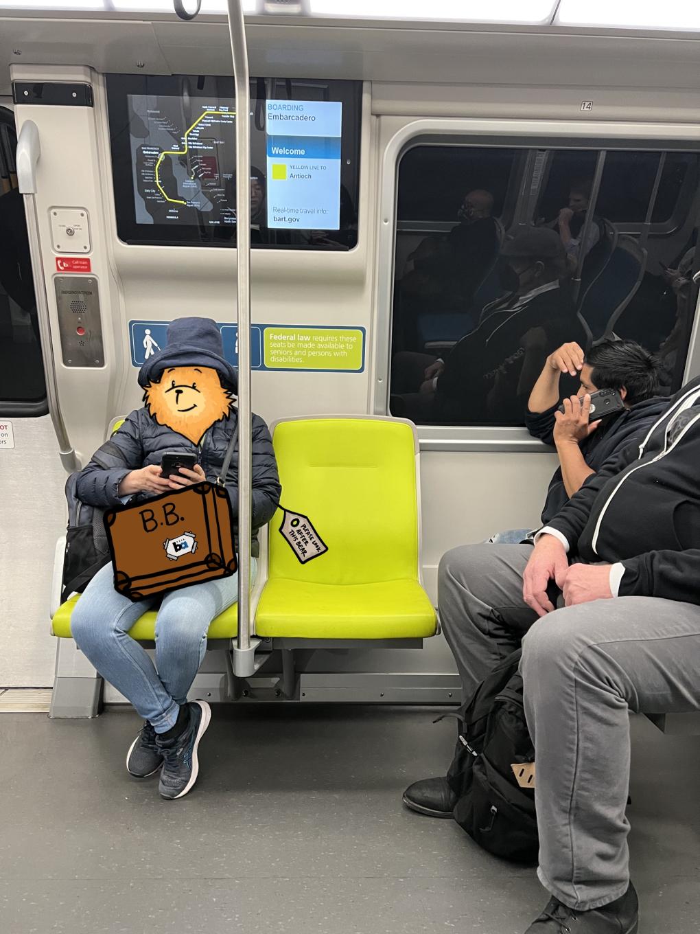 A scene on a BART train with a person sitting in a green seat with a Paddington Bear illustration over their head