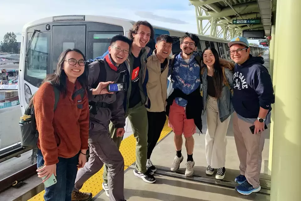 A group of people smile in front of a BART train