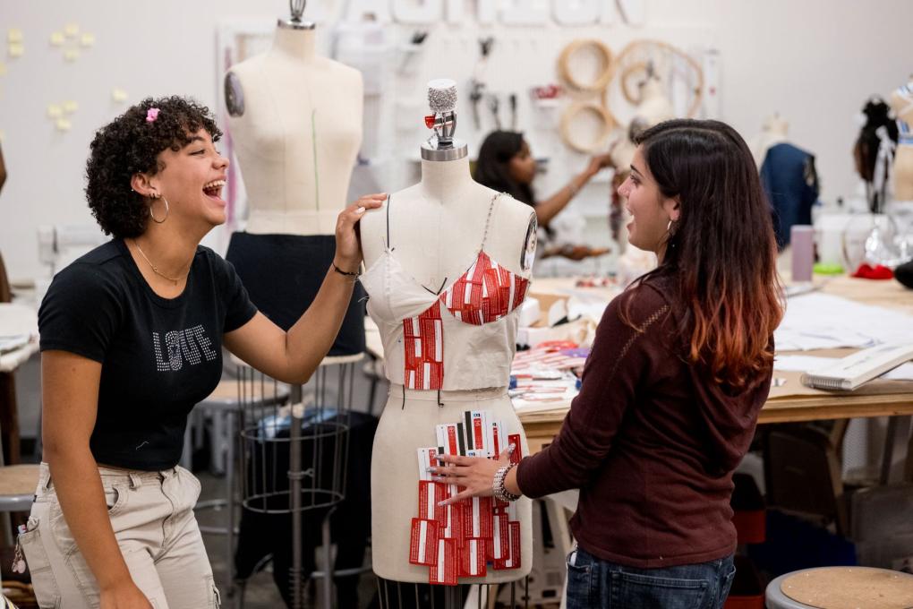 Two people standing in front of a mannequin laughing  