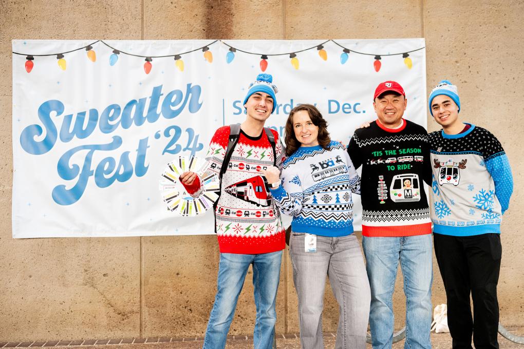 People standing in front of a sweater fest sign